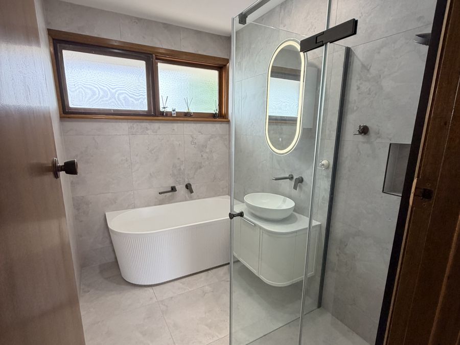 Completed bathroom with freestanding bath and frameless shower screen