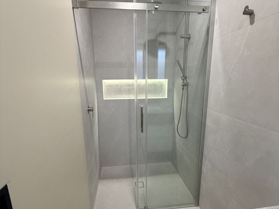 Walk-in shower with frameless sliding door and lit niche