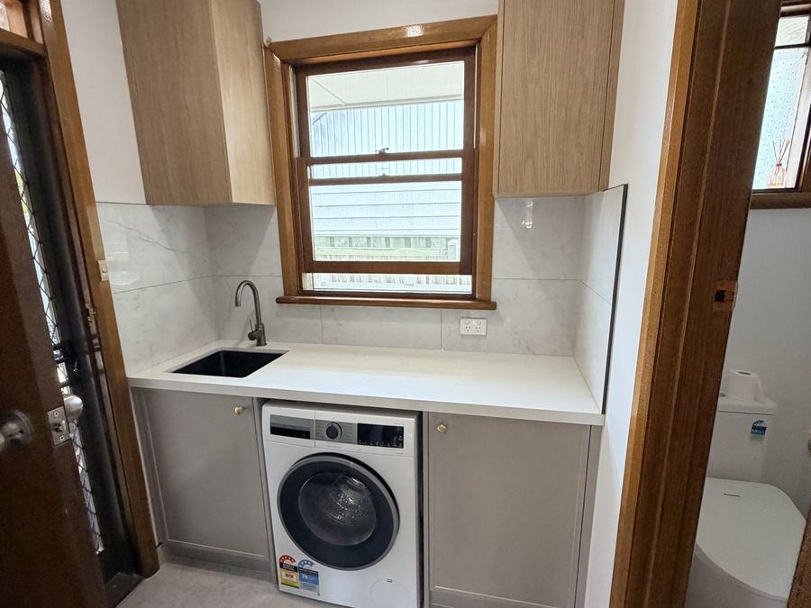 Completed laundry with overhead cabinetry and benchtop